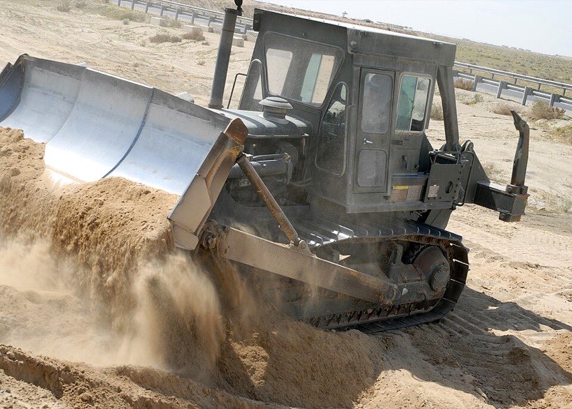 A bulldozer pushes sand and soil.