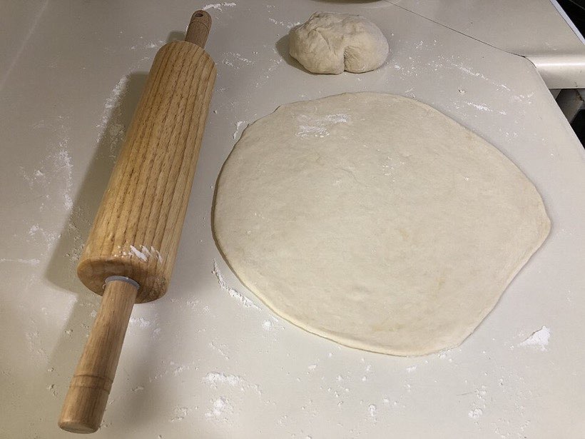Pushing with a rolling pin squashes dough into a flat roti.