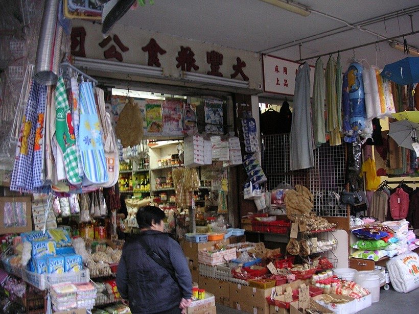 A shopkeeper adds up prices on paper or a calculator.
