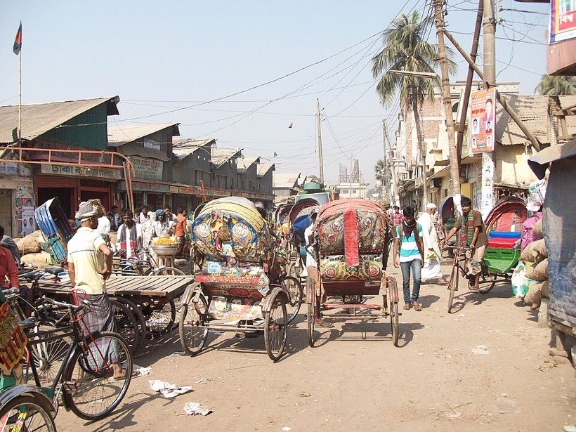 A busy road with rickshaws, buses and cars.